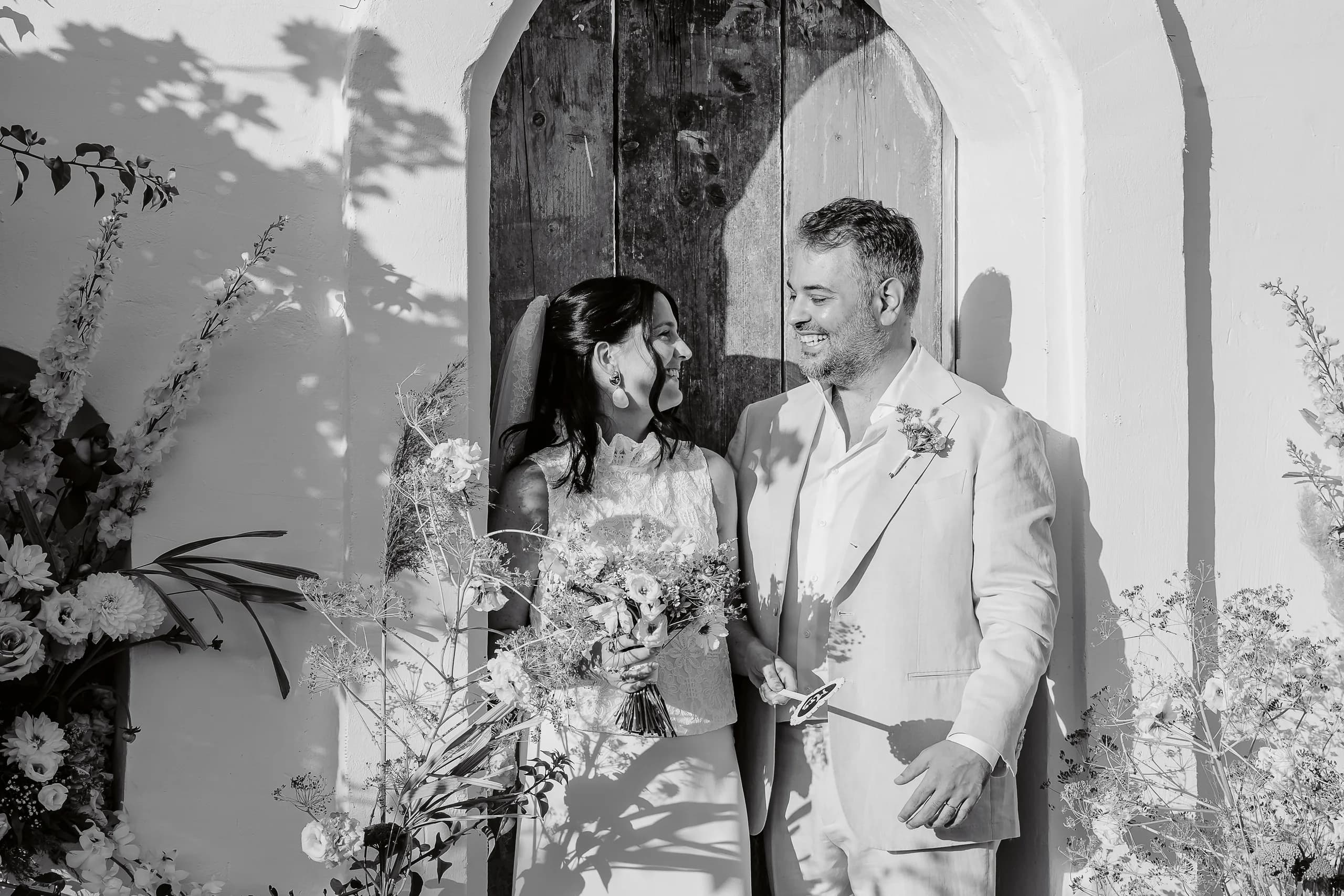 Clarisse et Maxime souriant devant la chapelle le jour de leur mariage